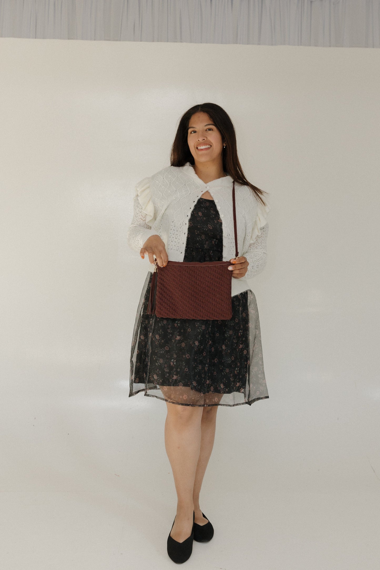 Woman holding a brown clutch against a plain background
