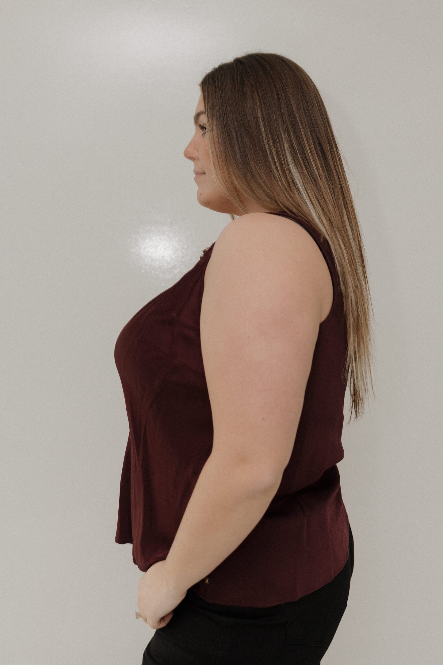 Woman wearing a burgundy sleeveless top against a plain background