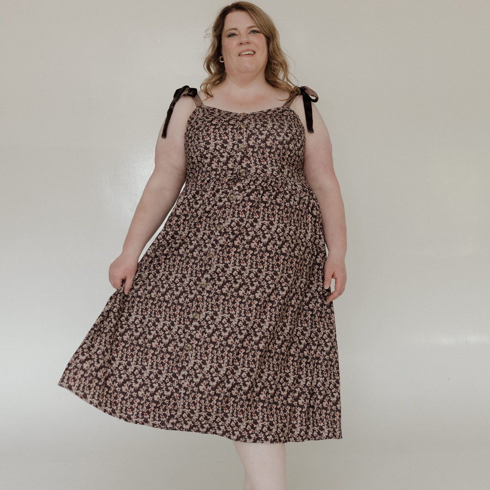Woman wearing a leopard print dress with black straps against a white background