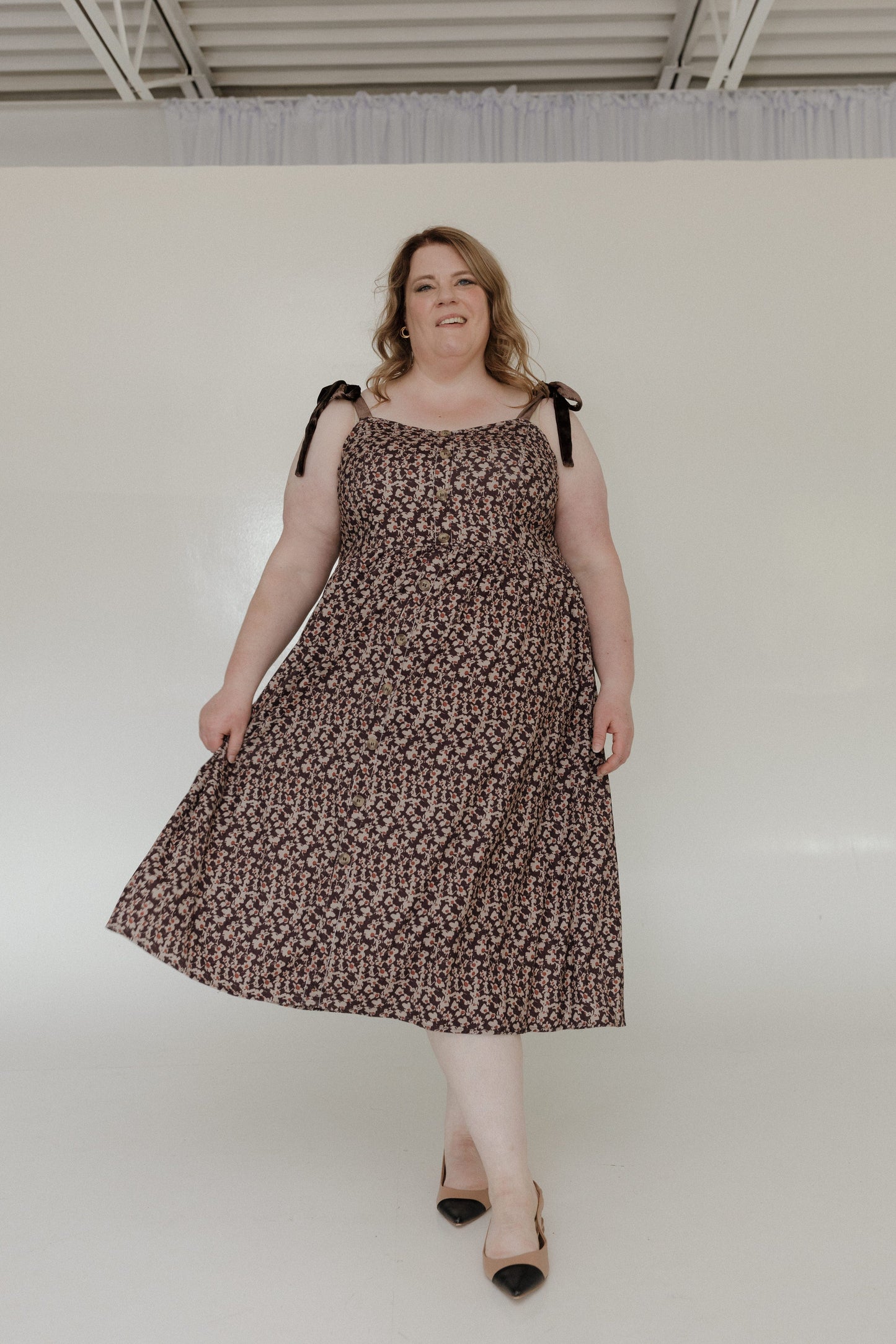 Woman wearing a leopard print dress with black straps against a white background
