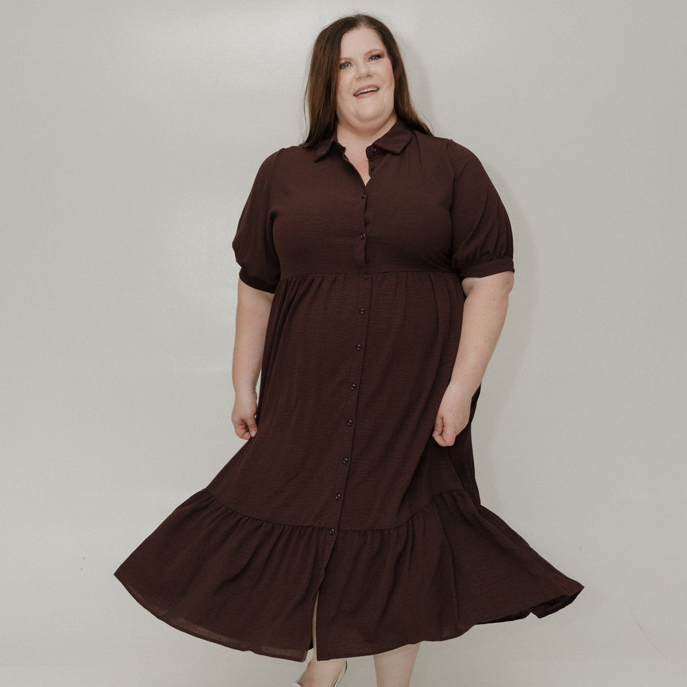 Woman wearing a brown dress standing against a white background