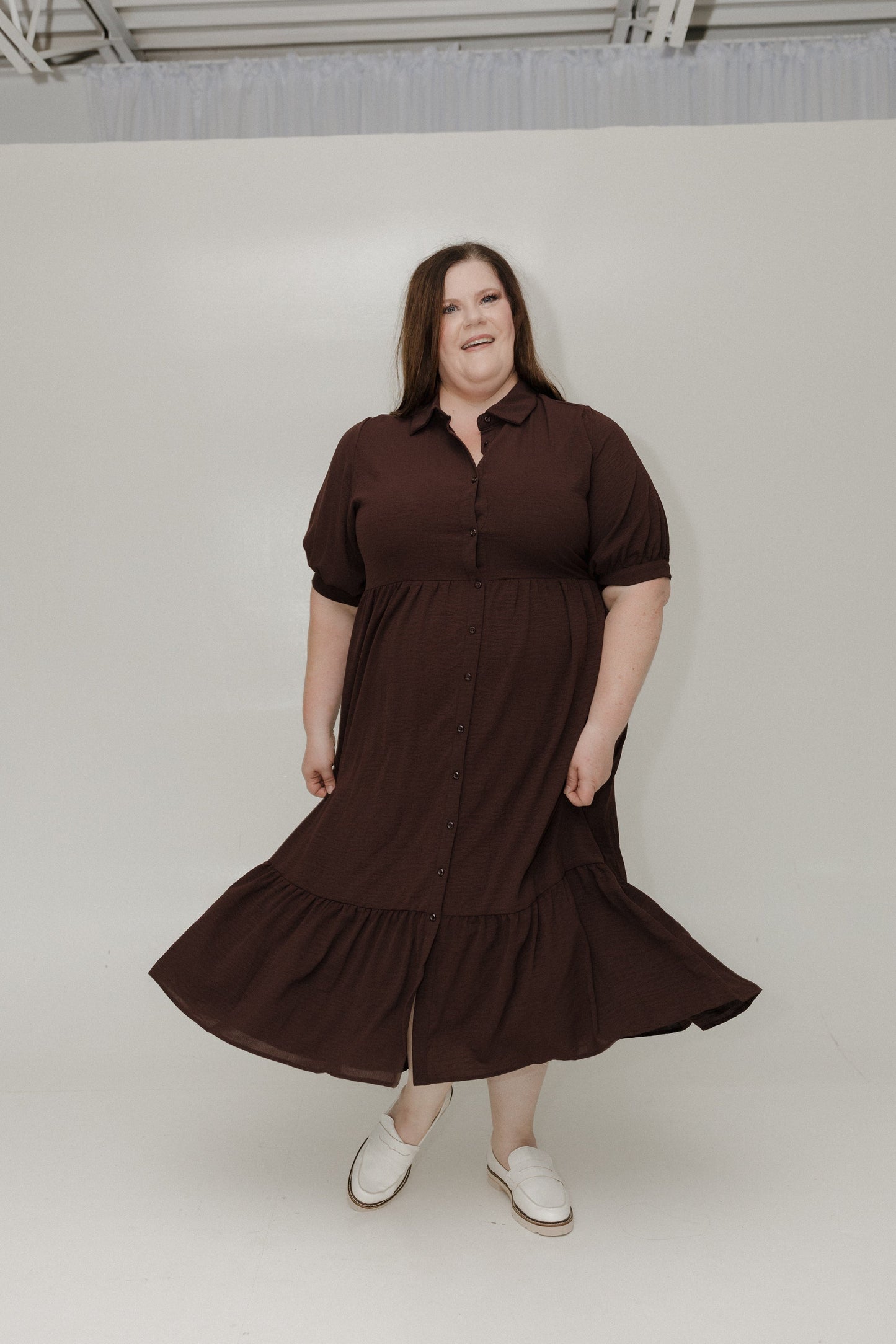 Woman wearing a brown dress standing against a white background