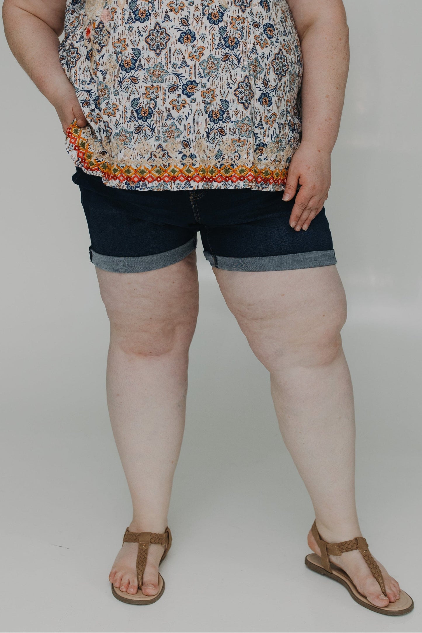 Woman wearing a floral top and denim shorts on a white background