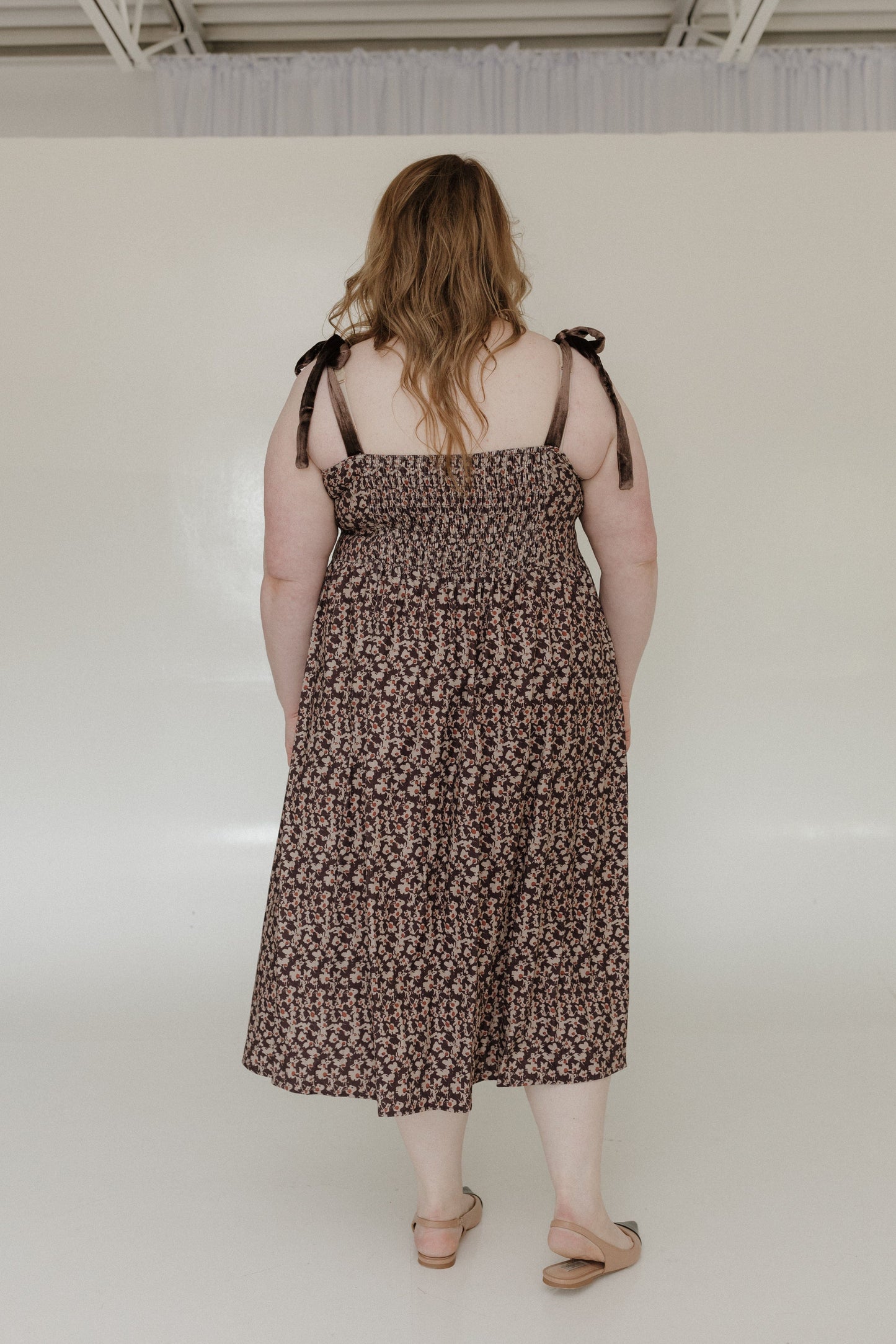 Person wearing a patterned dress with thin straps in an indoor setting