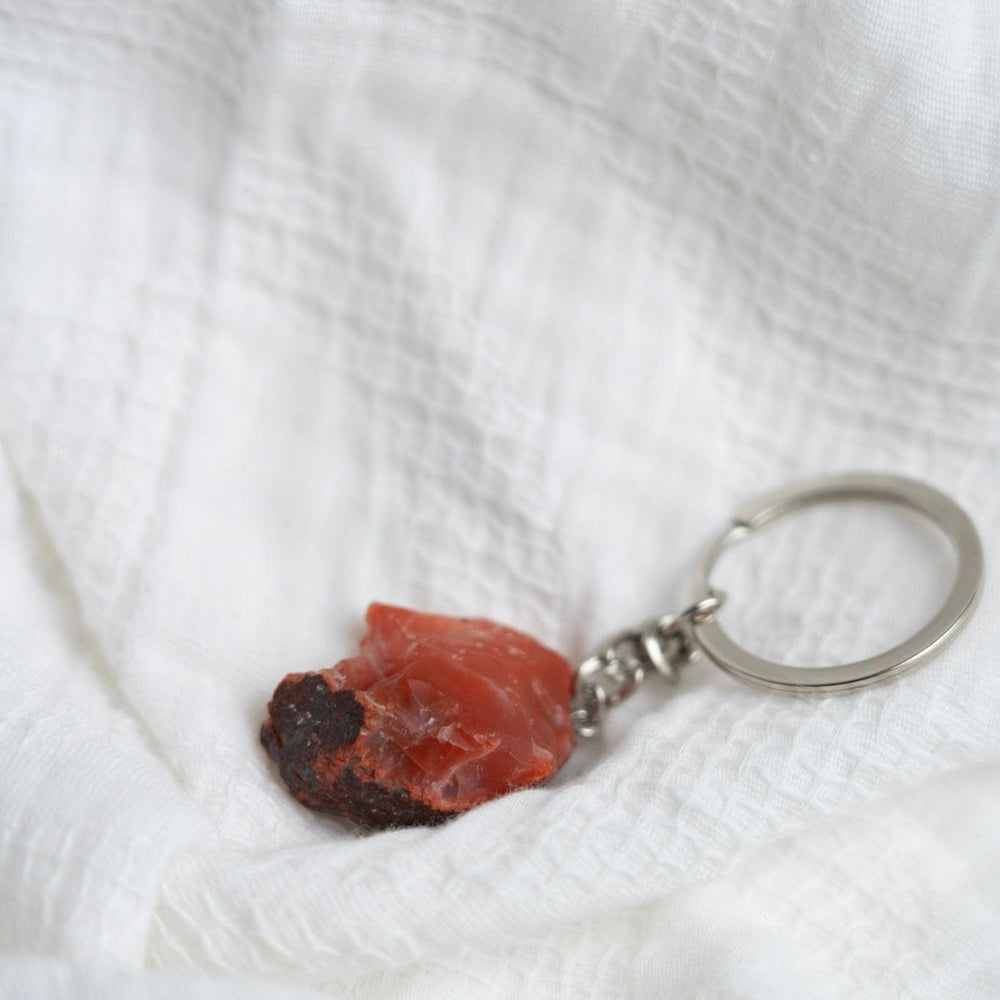Keychain with a red stone on a white textured fabric background