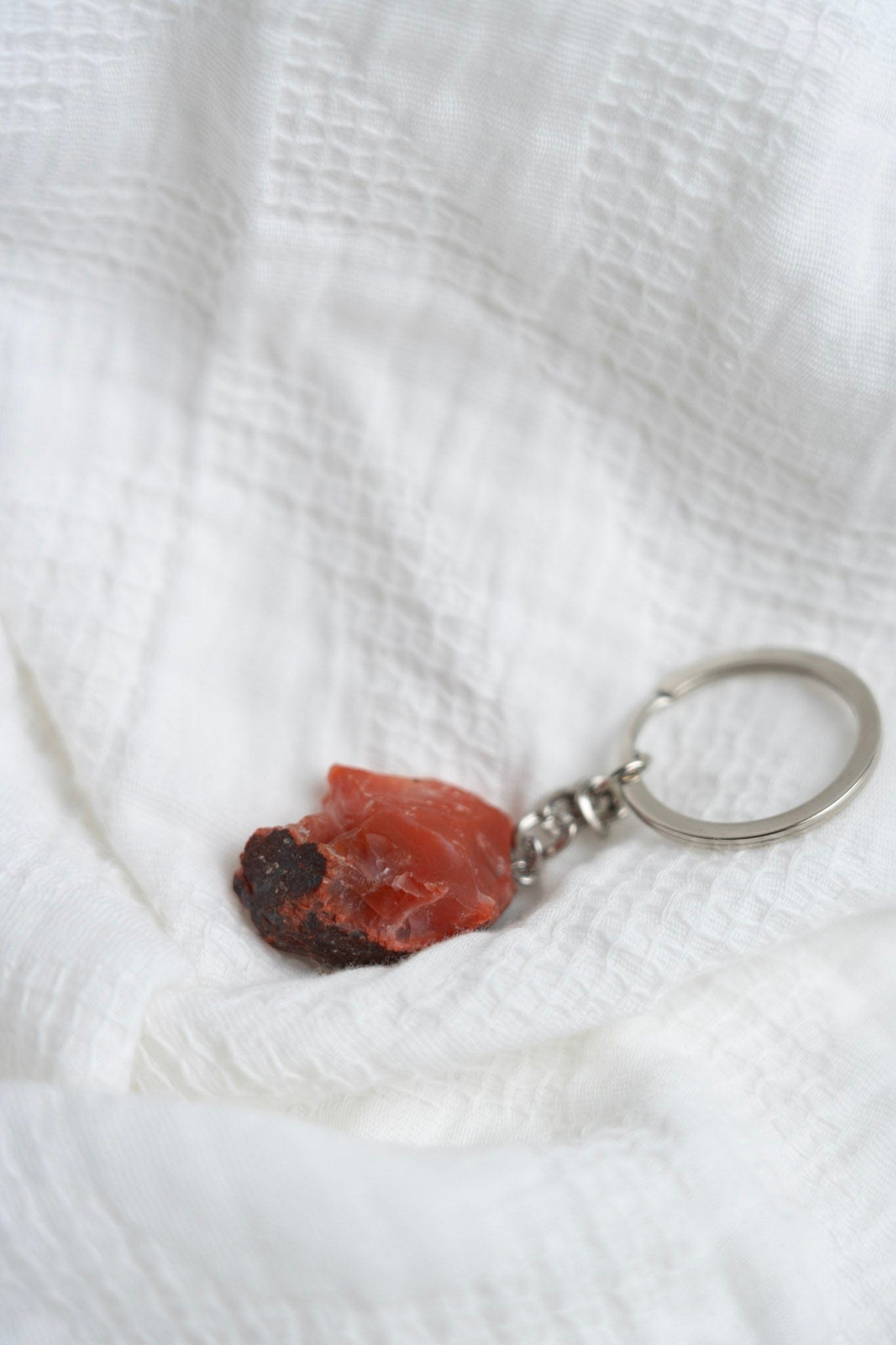 Keychain with a red stone on a white textured fabric background
