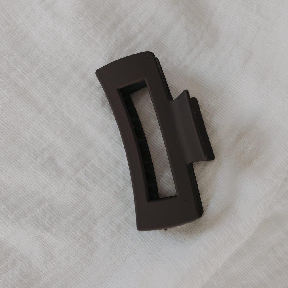 Charcoal claw clip on a white textured background