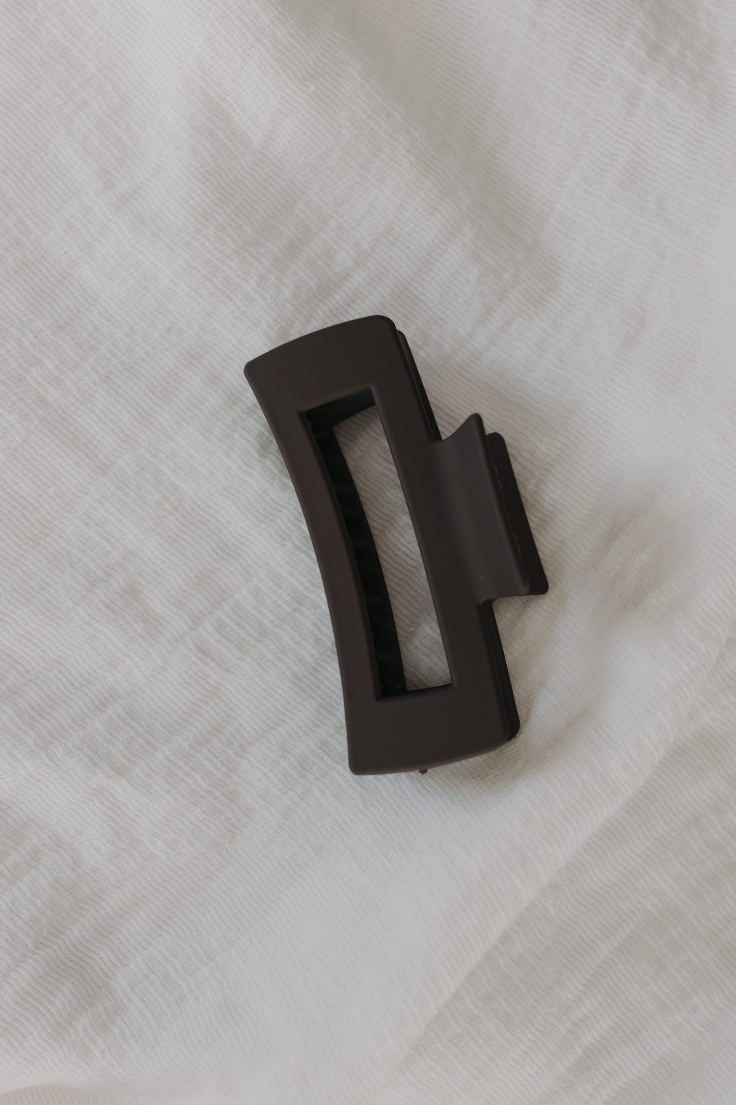Charcoal claw clip on a white textured background