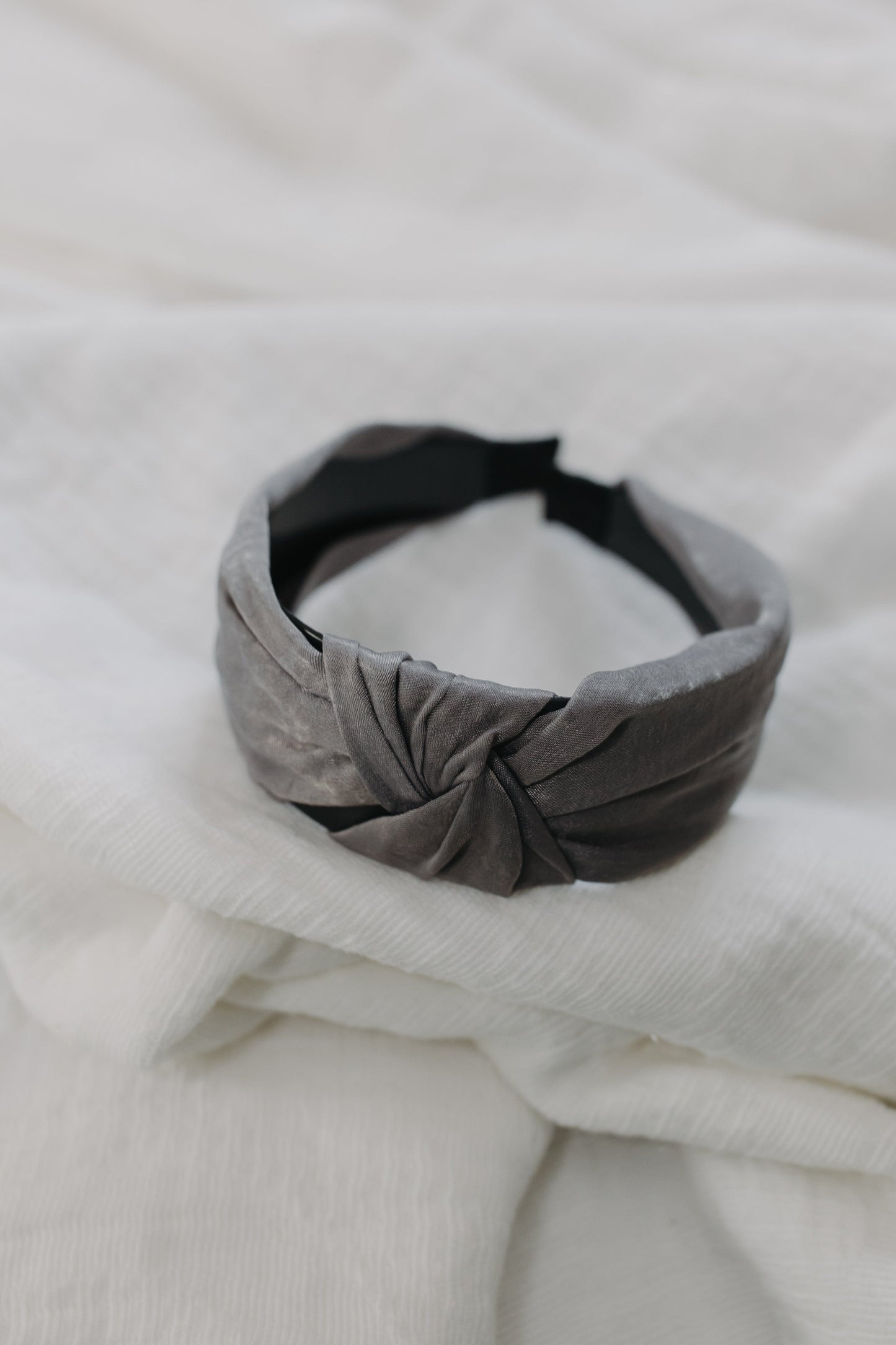 Gray knotted headband on a white fabric background
