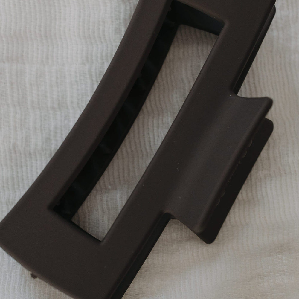 Charcoal claw clip on a textured beige surface