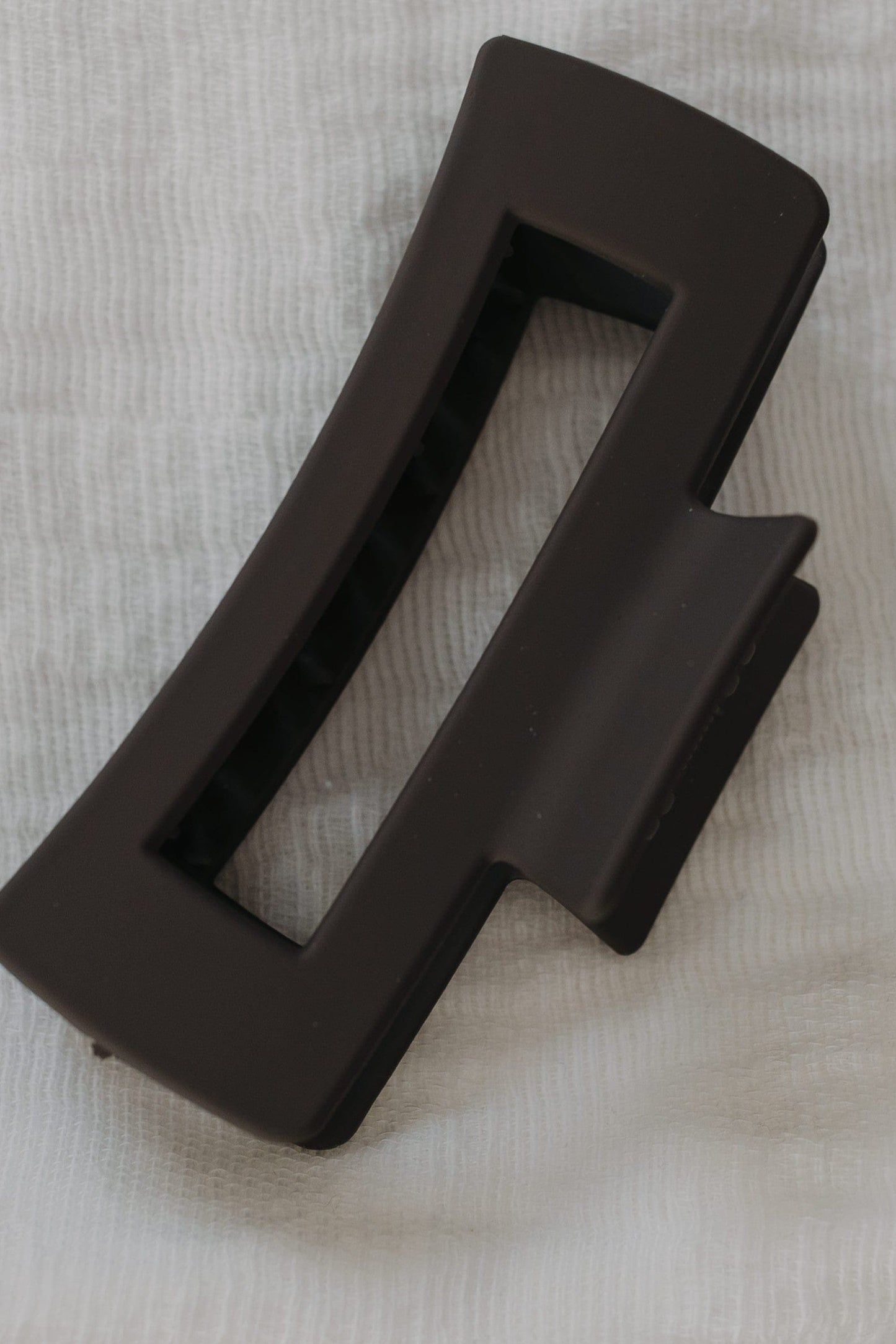 Charcoal claw clip on a textured beige surface