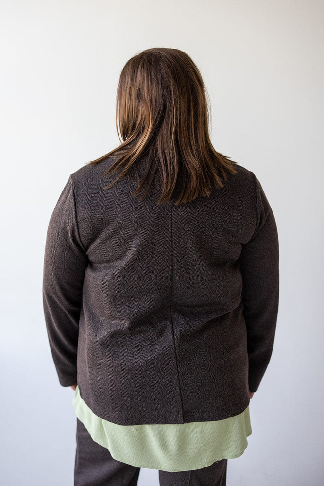 A person wearing the CHOCOLATE BLAZER IN TWEED from Love Marlow and dark pants stands with their back to the camera against a plain background.