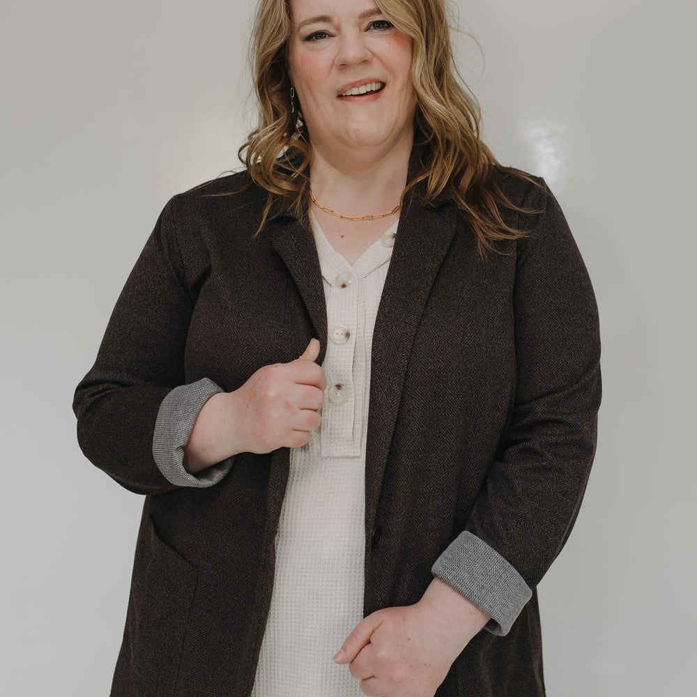Woman wearing a brown blazer over a white shirt on a plain background