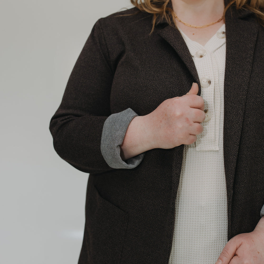 Person wearing a dark coat over a light shirt against a plain background
