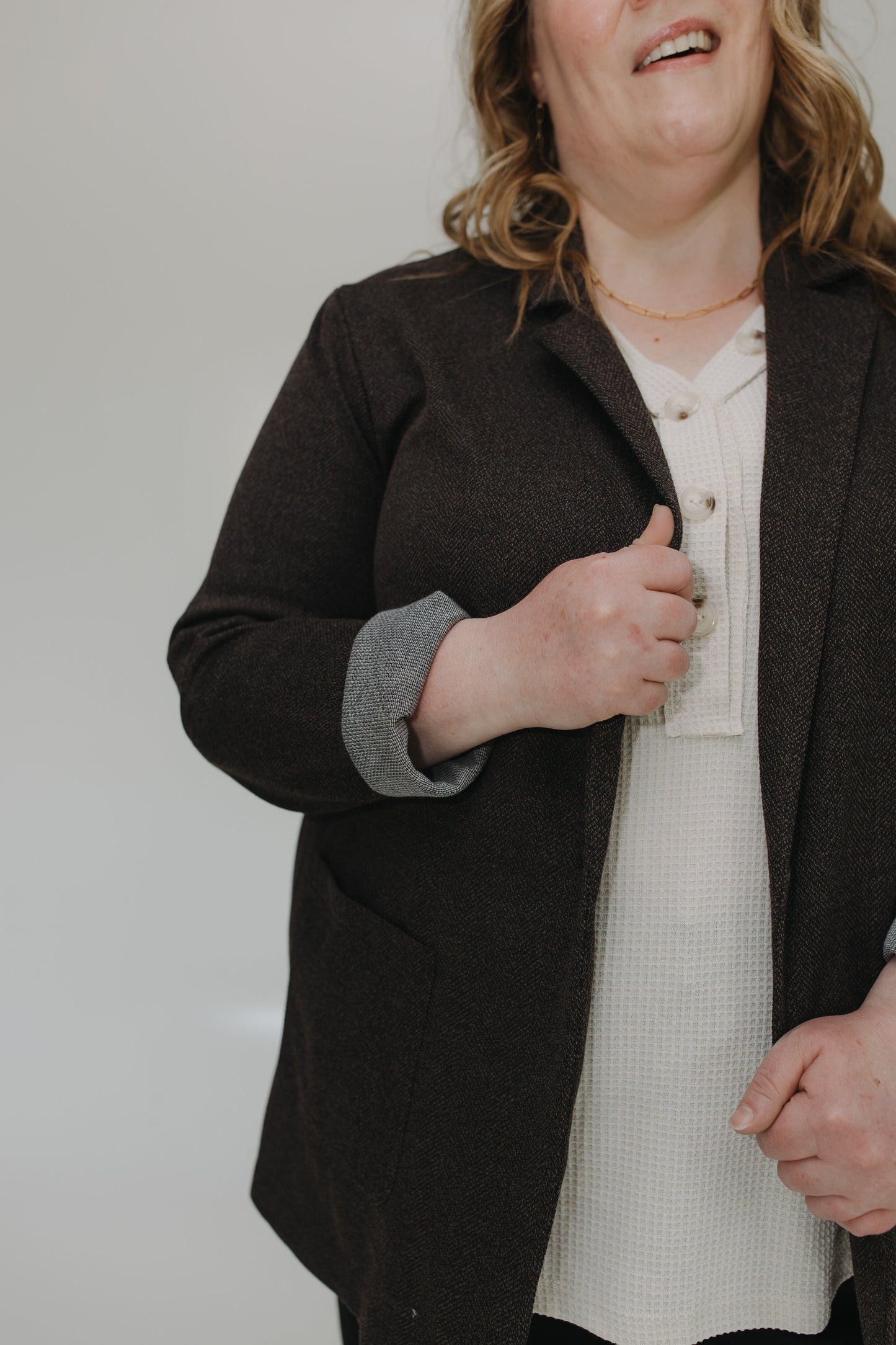 Person wearing a dark coat over a light shirt against a plain background