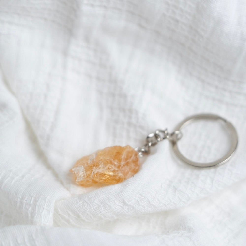 Keychain with a Citrine stone pendant on a white textured fabric background