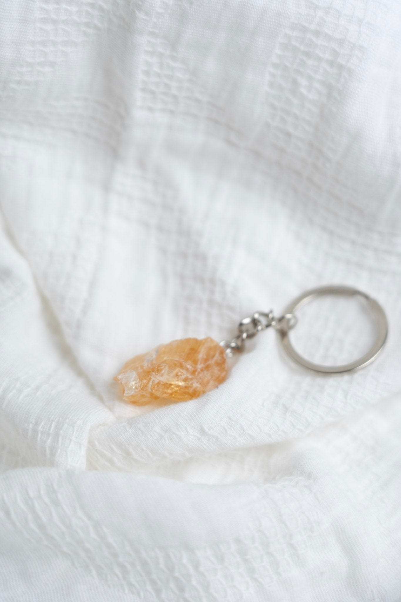Keychain with a Citrine stone pendant on a white textured fabric background