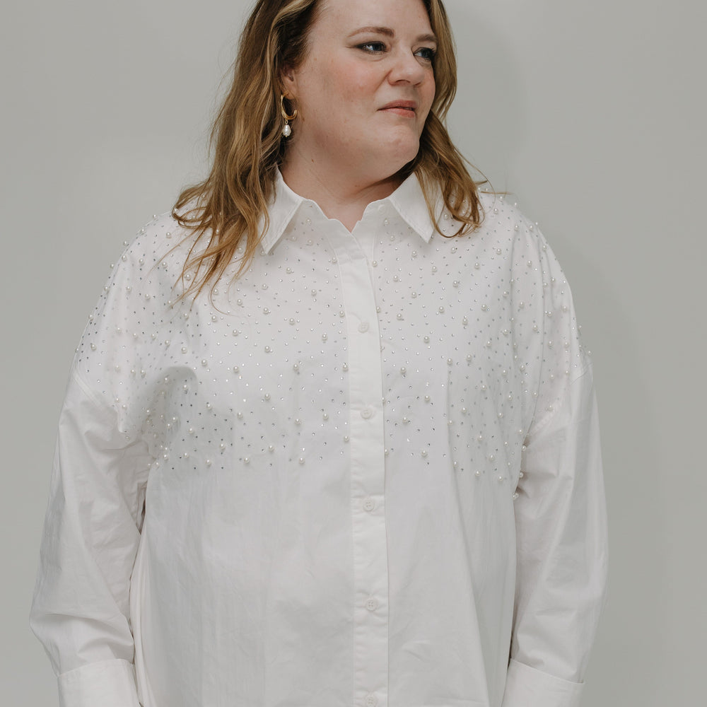Woman wearing a white button-up shirt against a plain background