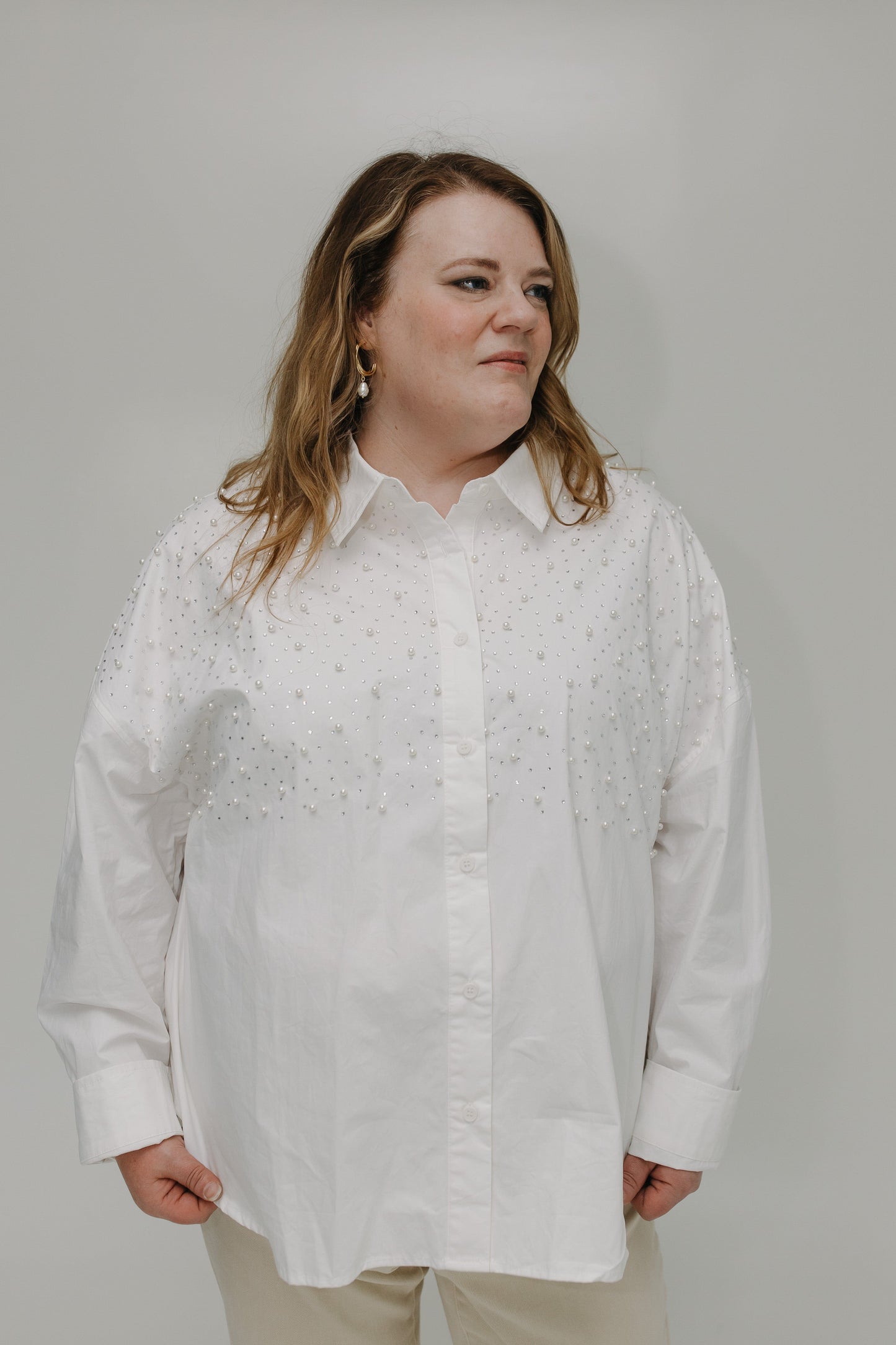Woman wearing a white button-up shirt against a plain background