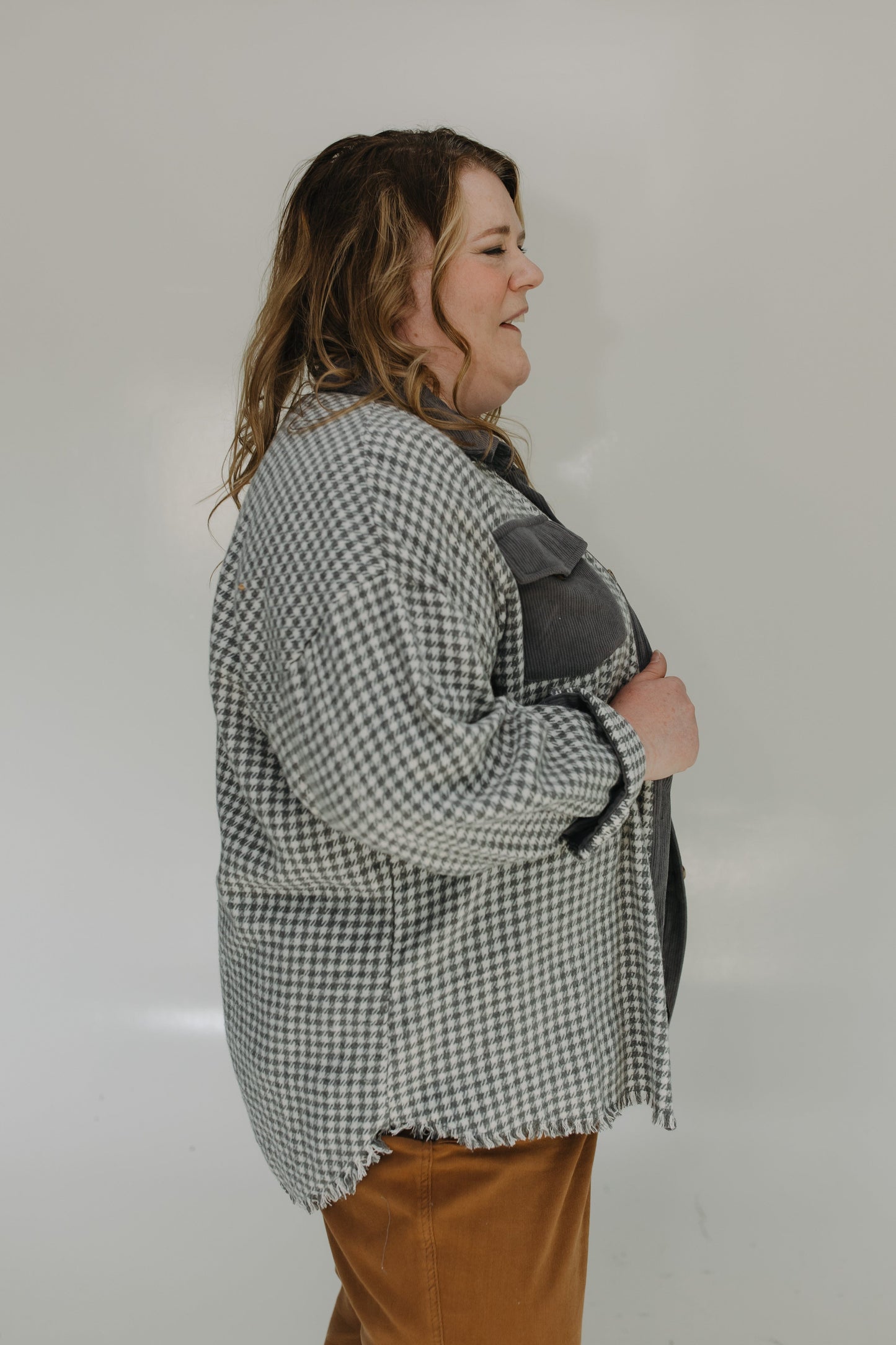 Person wearing a checkered shirt over a black jacket on a plain background