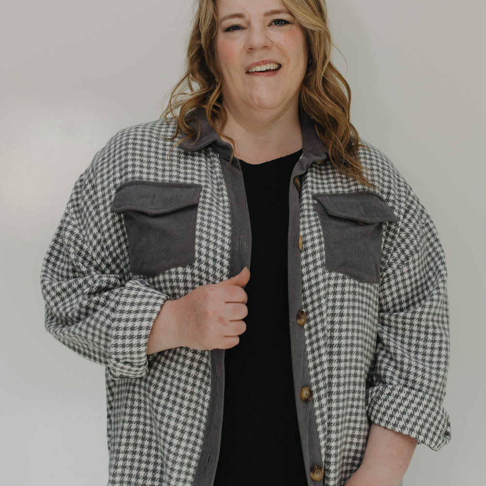 Person wearing a checkered shirt over a black top with a plain background