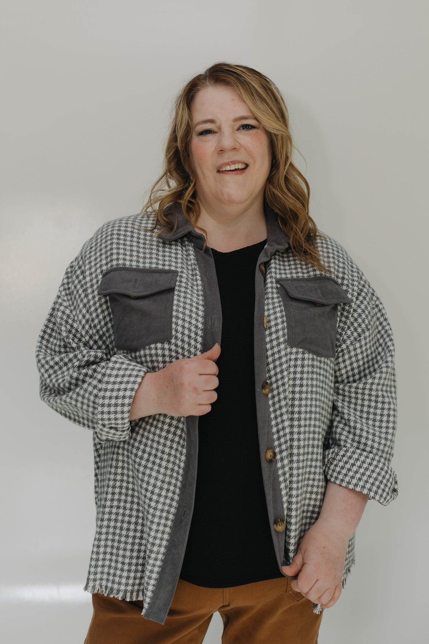 Person wearing a checkered shirt over a black top with a plain background
