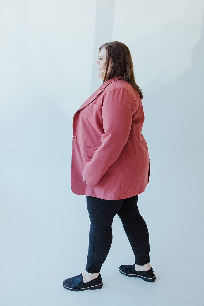 A person stands with their back to the camera, making a timelessly chic statement in a Yesta CLASSIC NOTCHED BLAZER in pink, paired with black pants and sleek black shoes.