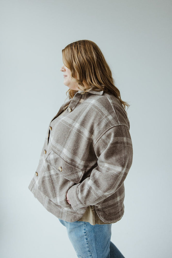 A person with wavy hair is wearing the CLASSIC SHACKET IN EARTH TONES by Yesta and jeans, standing sideways against a plain background.