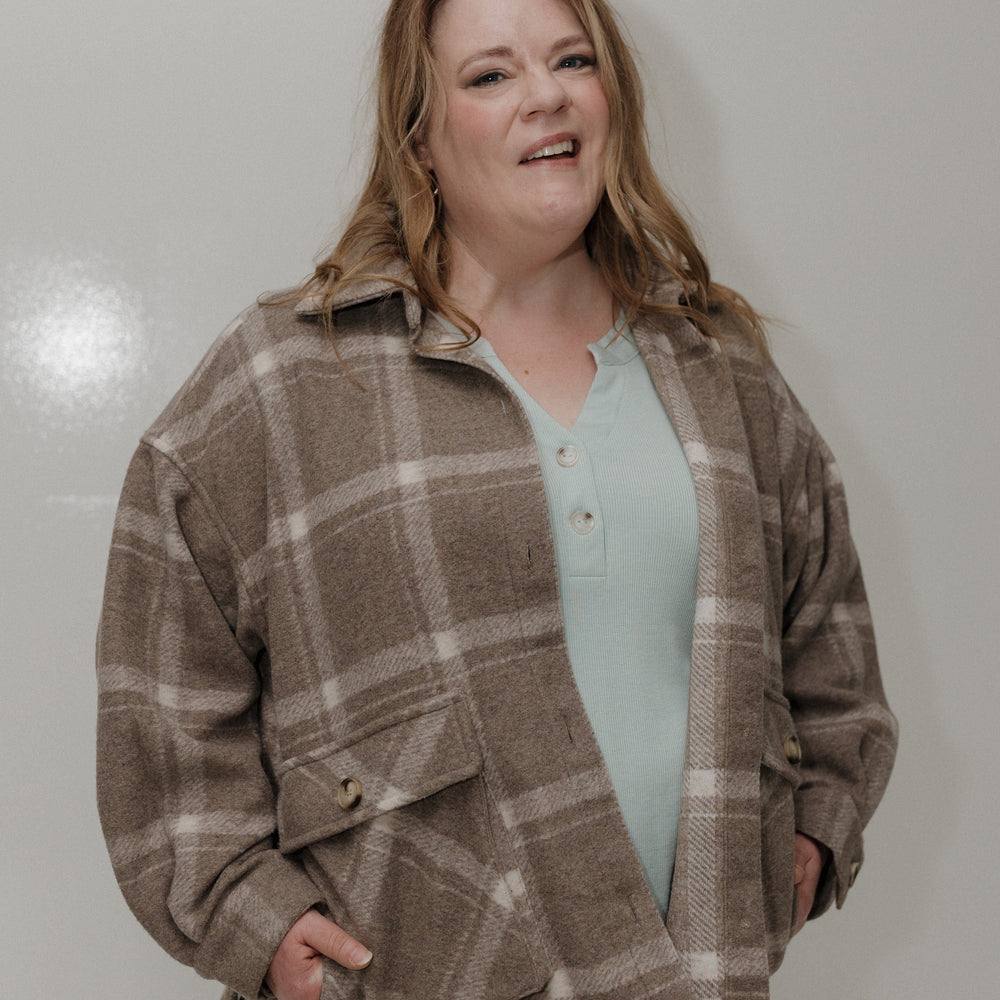 Woman wearing a plaid jacket over a light blue shirt against a white background