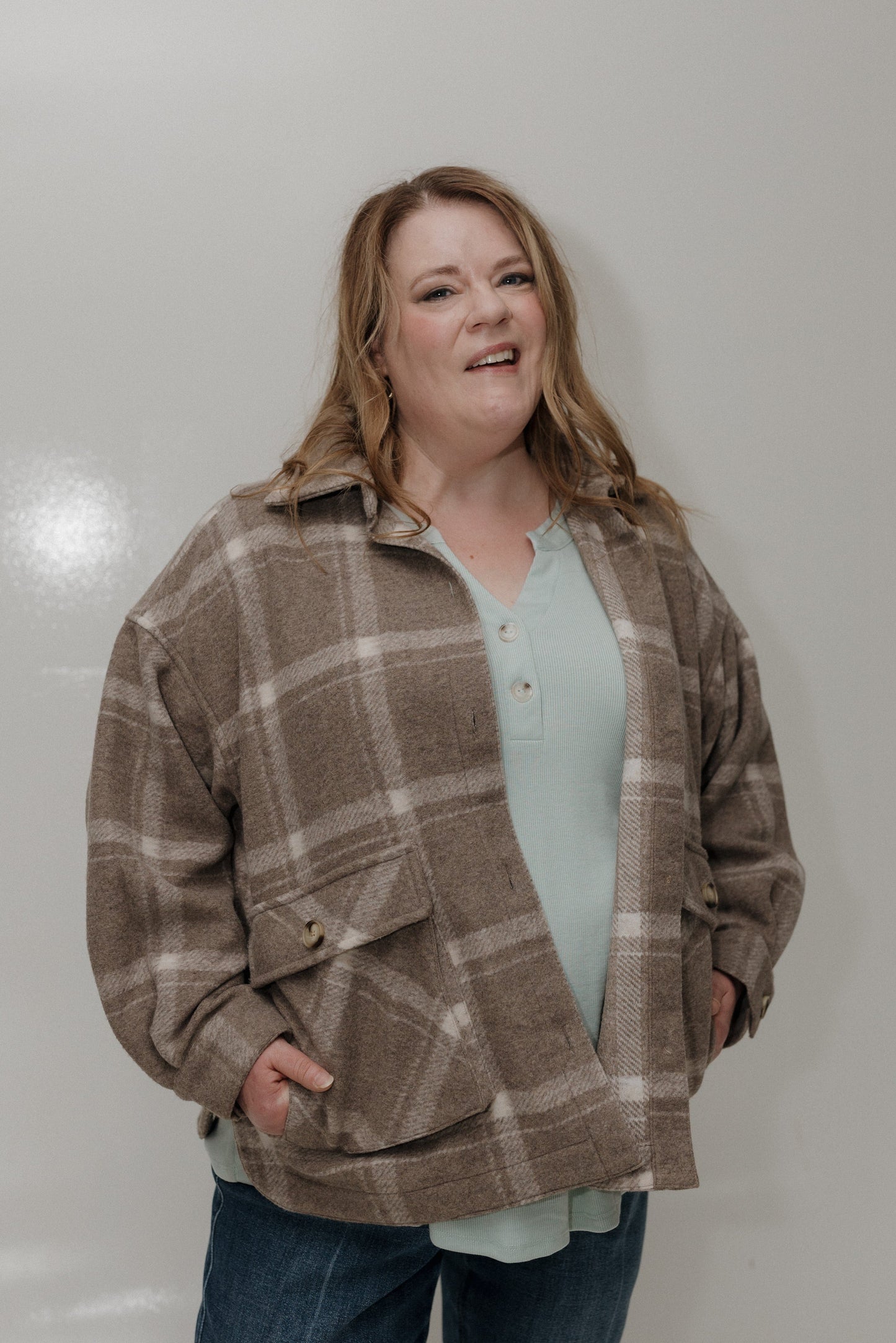 Woman wearing a plaid jacket over a light blue shirt against a white background