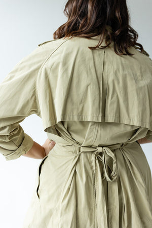 Back view of an individual wearing the Yesta CLASSIC TRENCH COAT, which includes a tied belt and double-breasted buttons, made from water-resistant fabric.