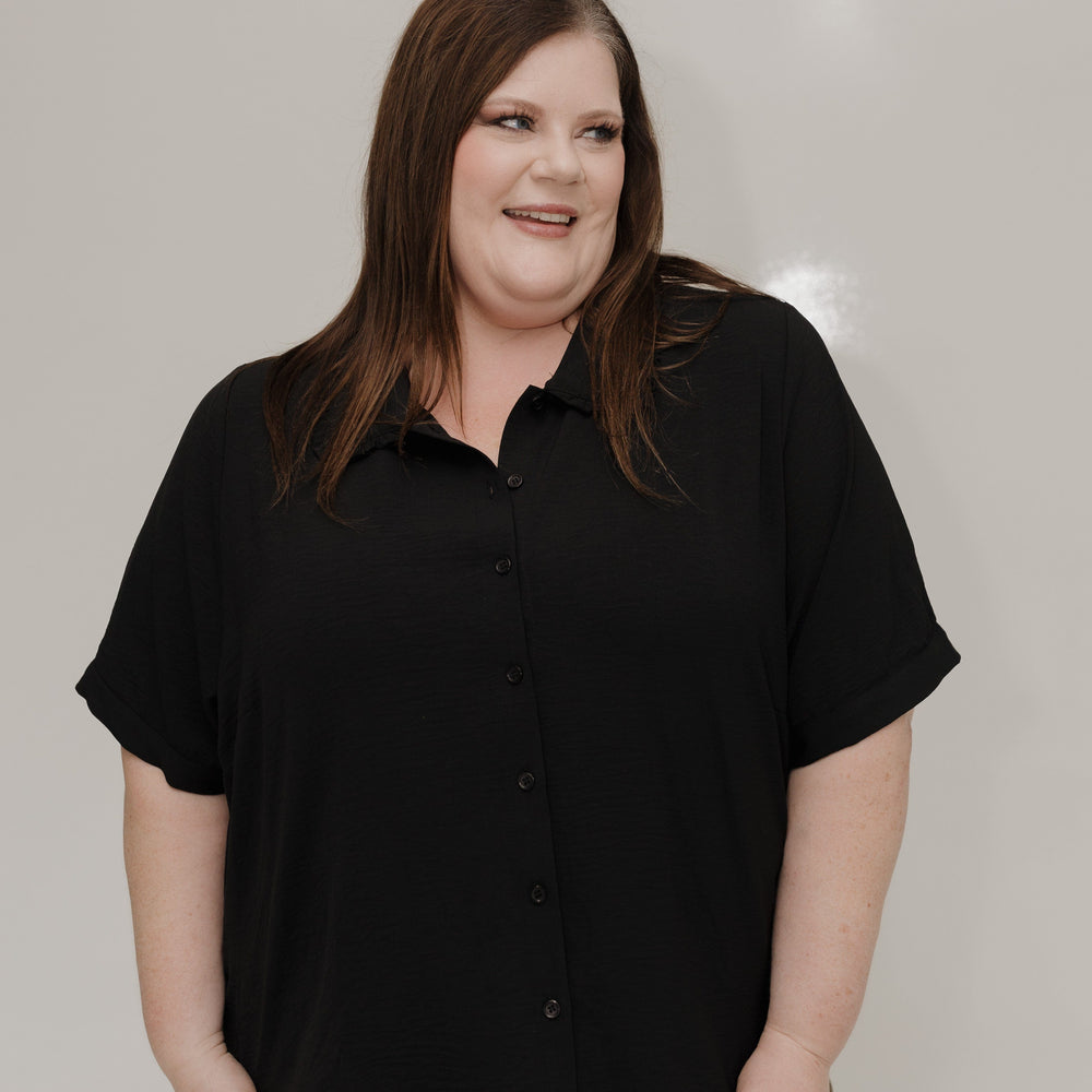 Person wearing a black shirt and brown pants against a plain background