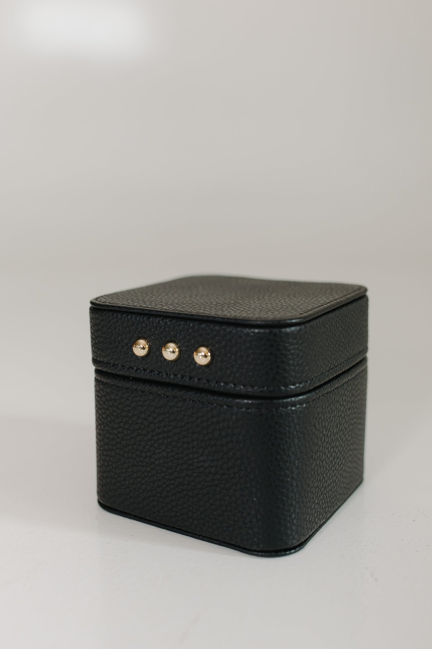 Black textured jewelry box with gold accents on a light gray background
