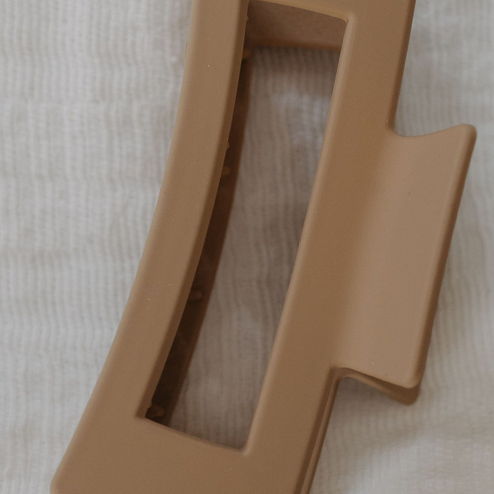 Cool Sand plastic claw clip on a white fabric background