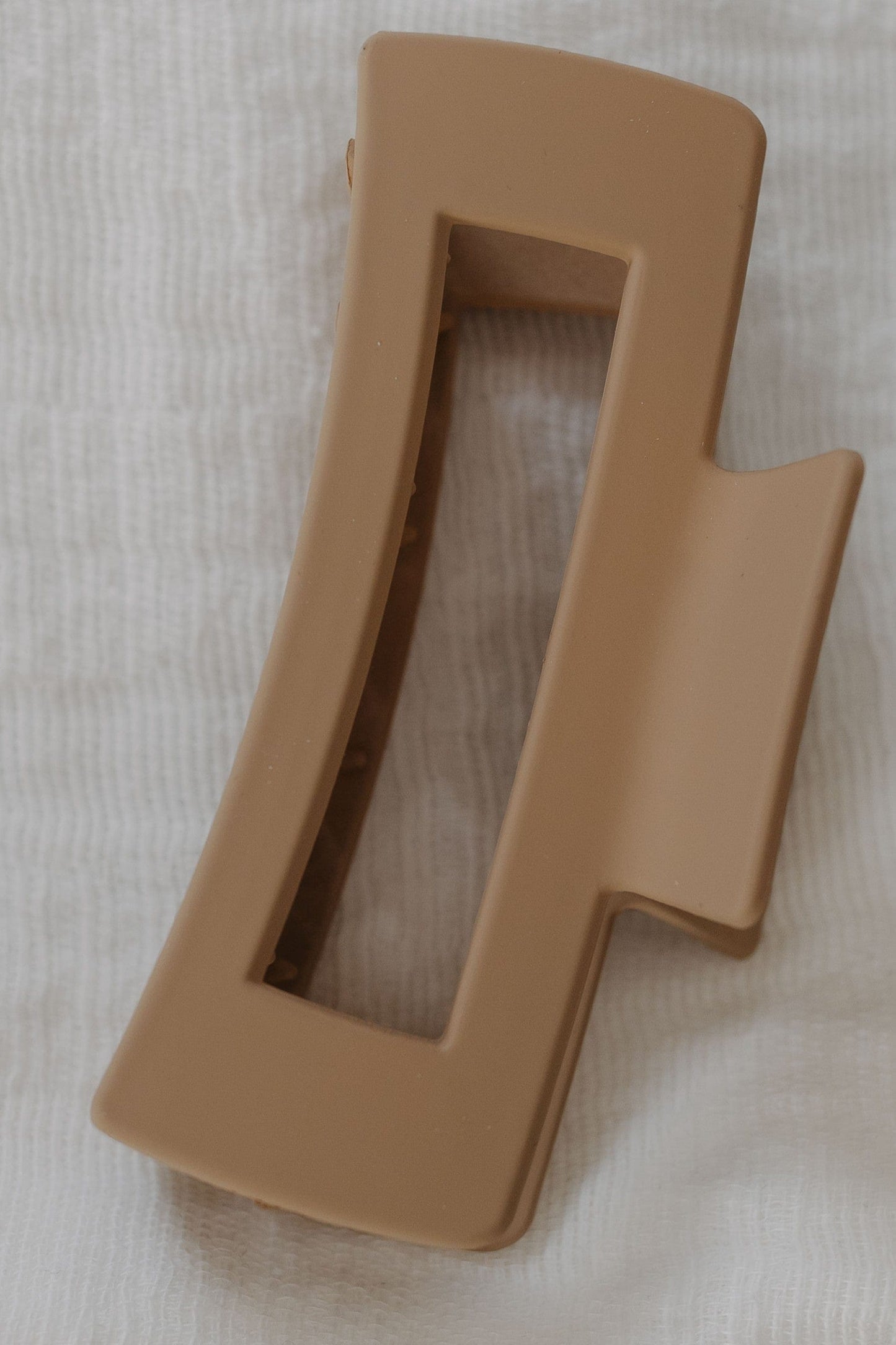 Cool Sand plastic claw clip on a white fabric background