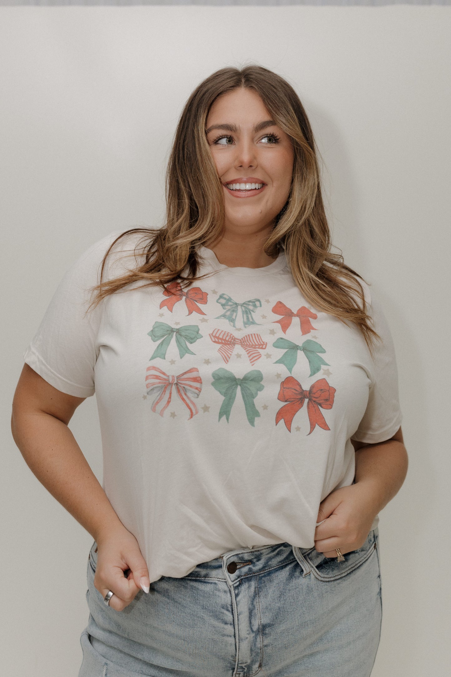 Woman wearing a t-shirt with bow designs against a plain background