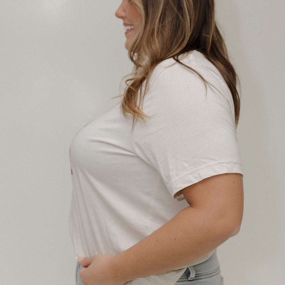 Woman wearing a white t-shirt and light blue jeans against a plain background