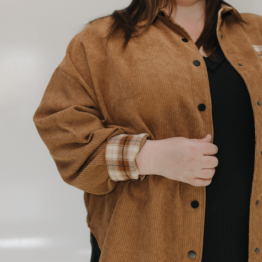 Person wearing a brown corduroy jacket with a plain background