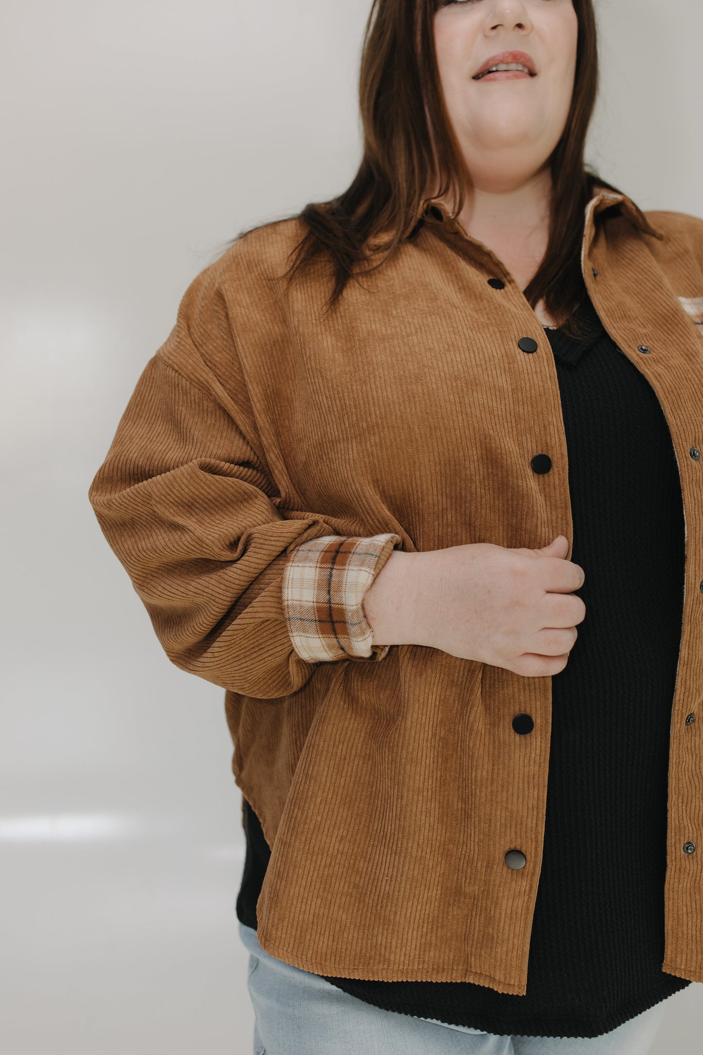 Person wearing a brown corduroy jacket with a plain background