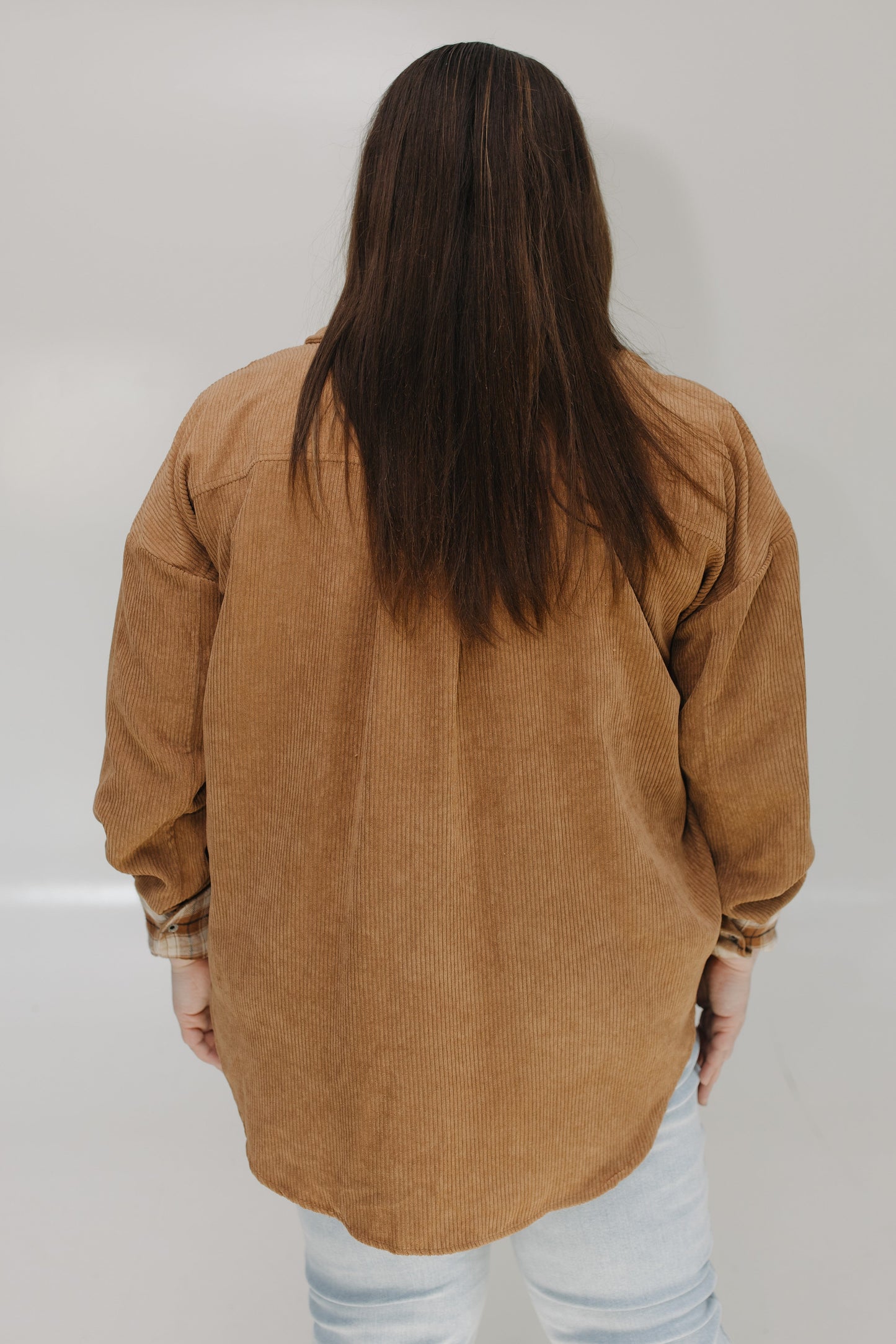 Person wearing a brown corduroy shirt against a plain background