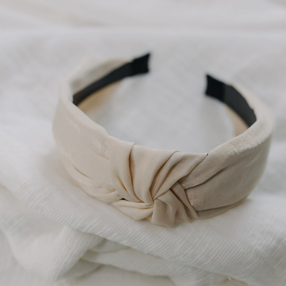 cream matte satin headband with white textured background. 