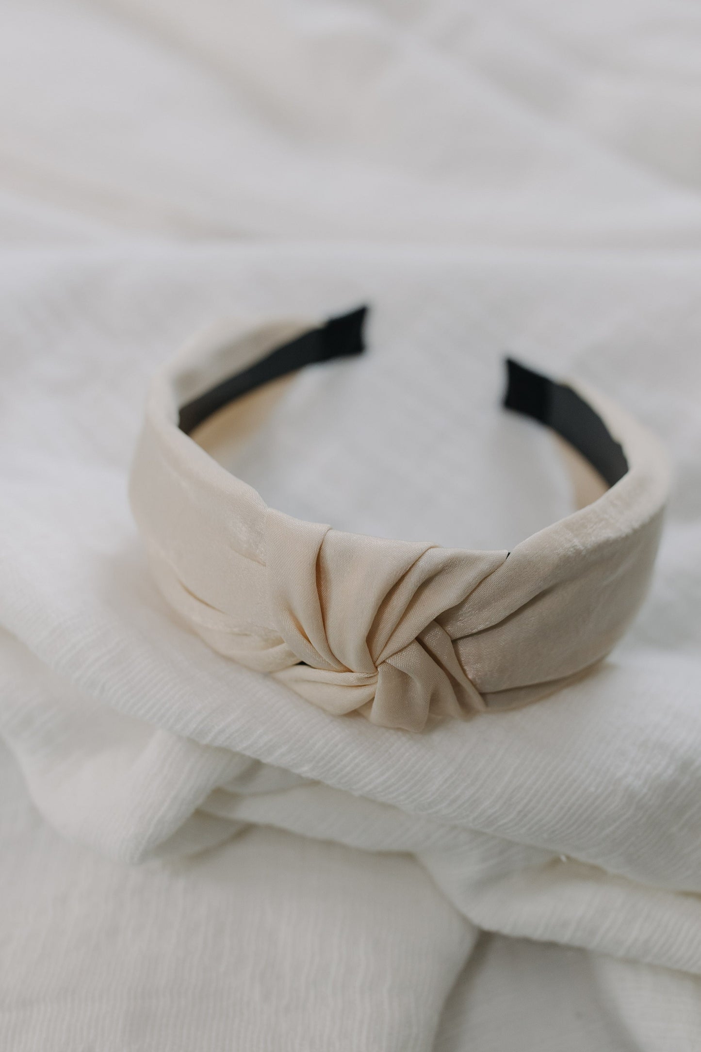 cream matte satin headband with white textured background. 