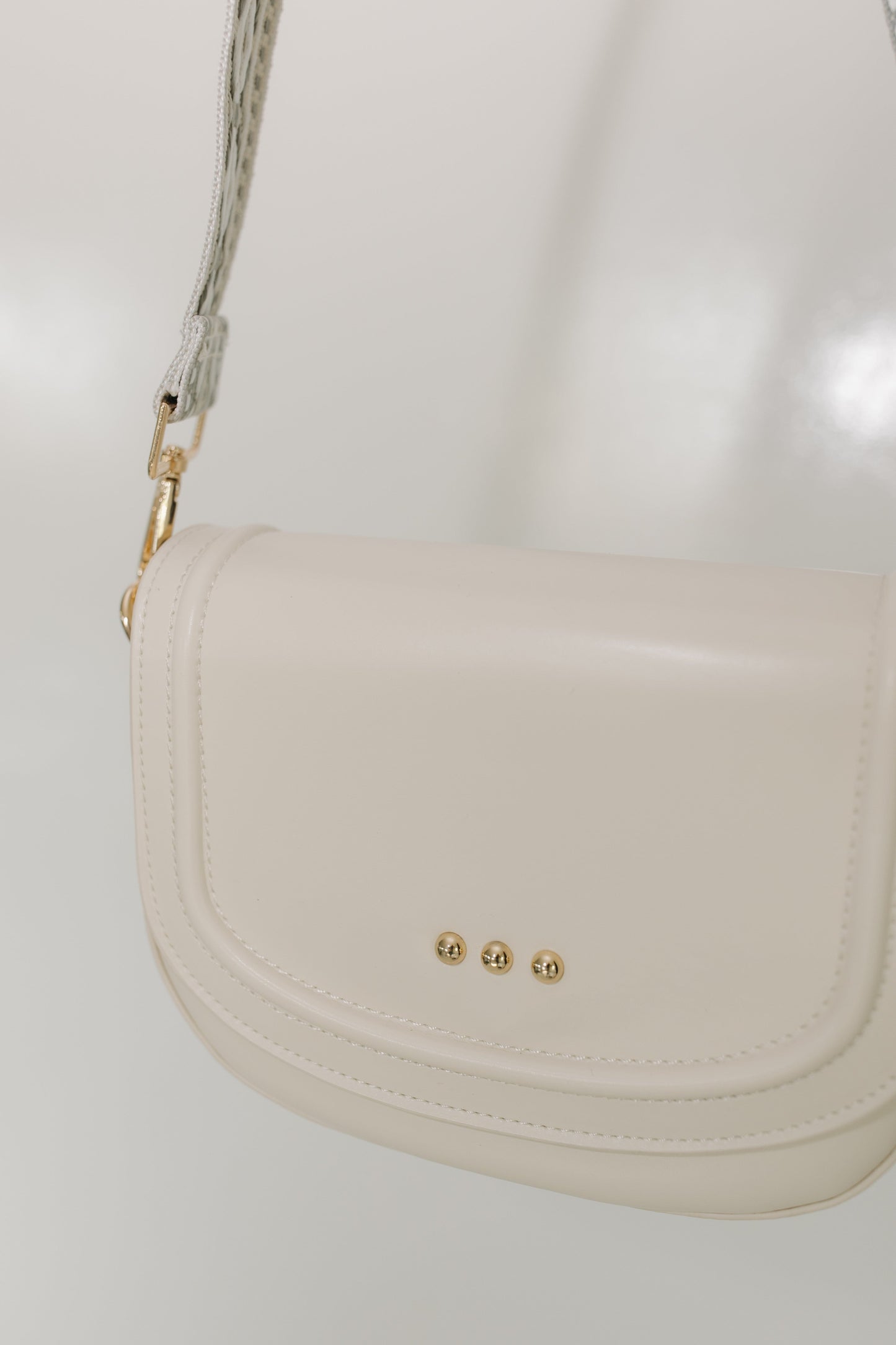 Cream handbag with gold accents on a white background
