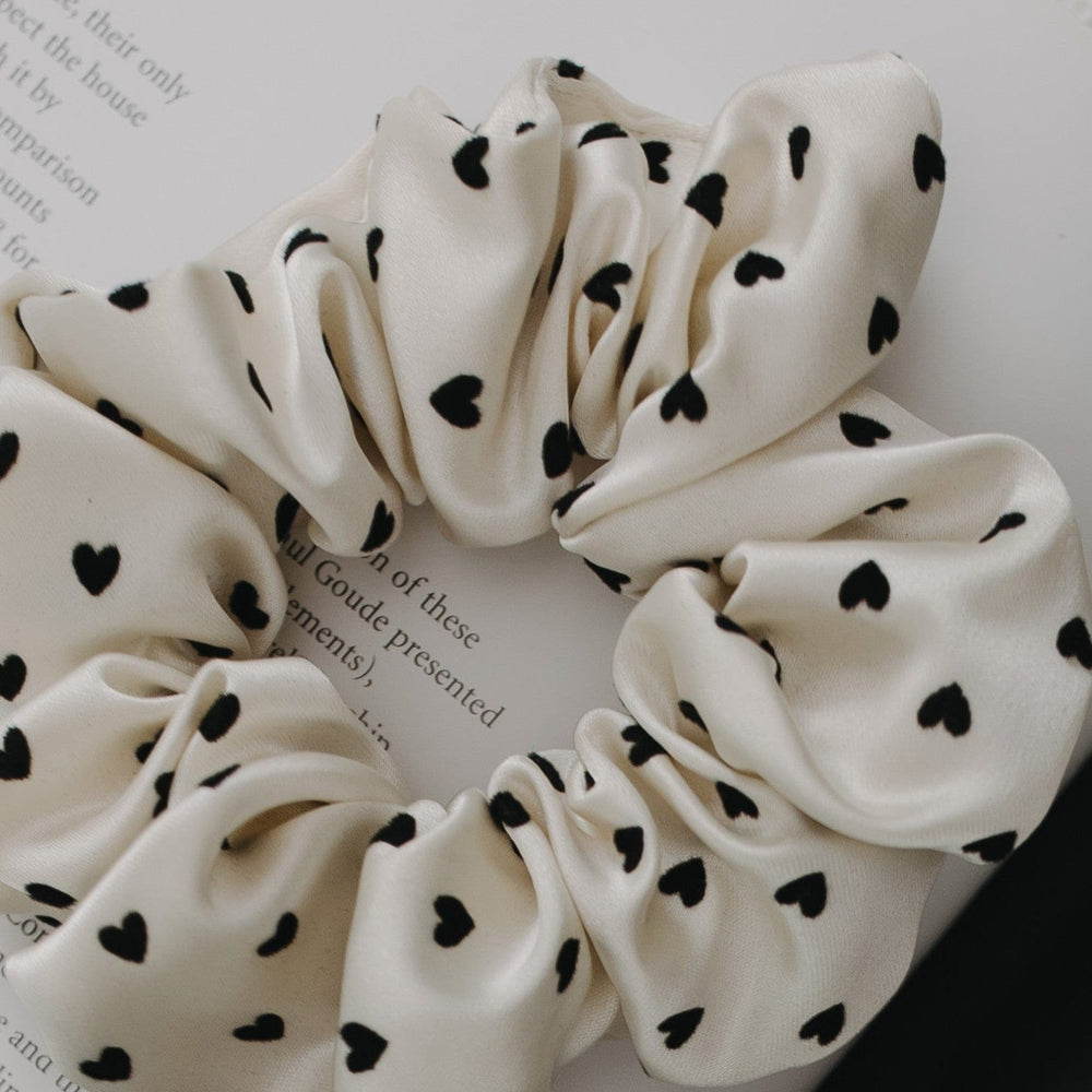 White scrunchie with black heart patterns on a white background