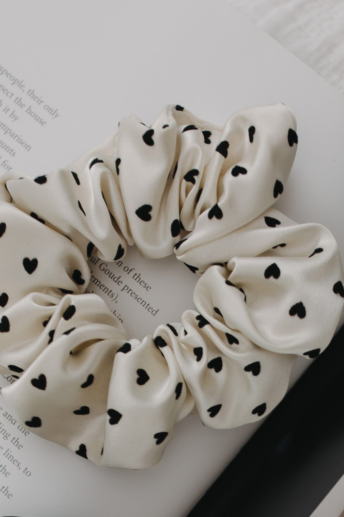 White scrunchie with black heart patterns on a white background