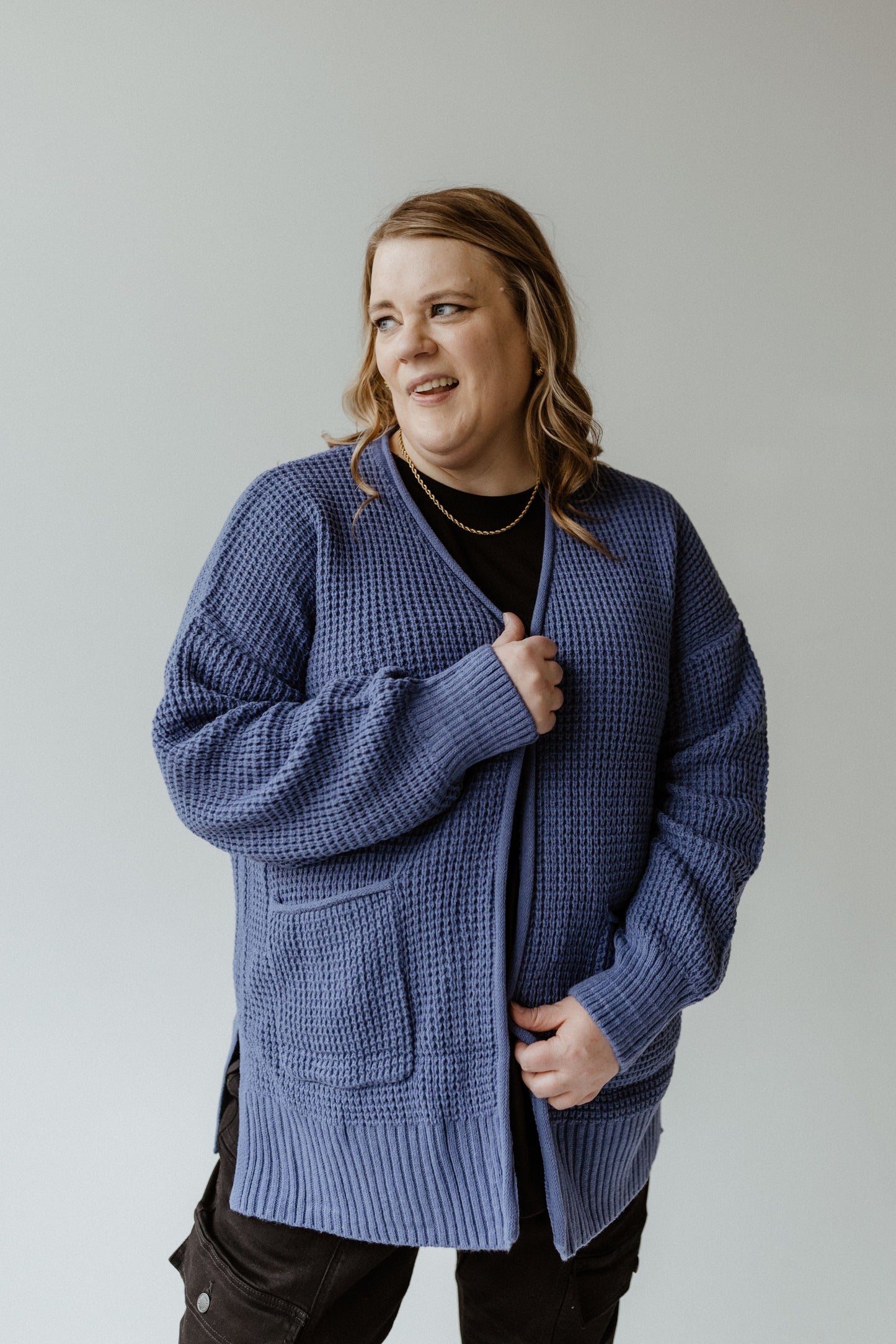 A person wearing a French Blue crochet knit cardigan over a black shirt stands against a plain background.