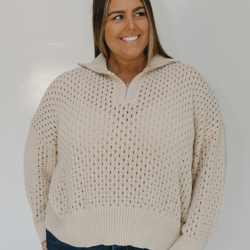 Woman wearing a beige sweater with a white background
