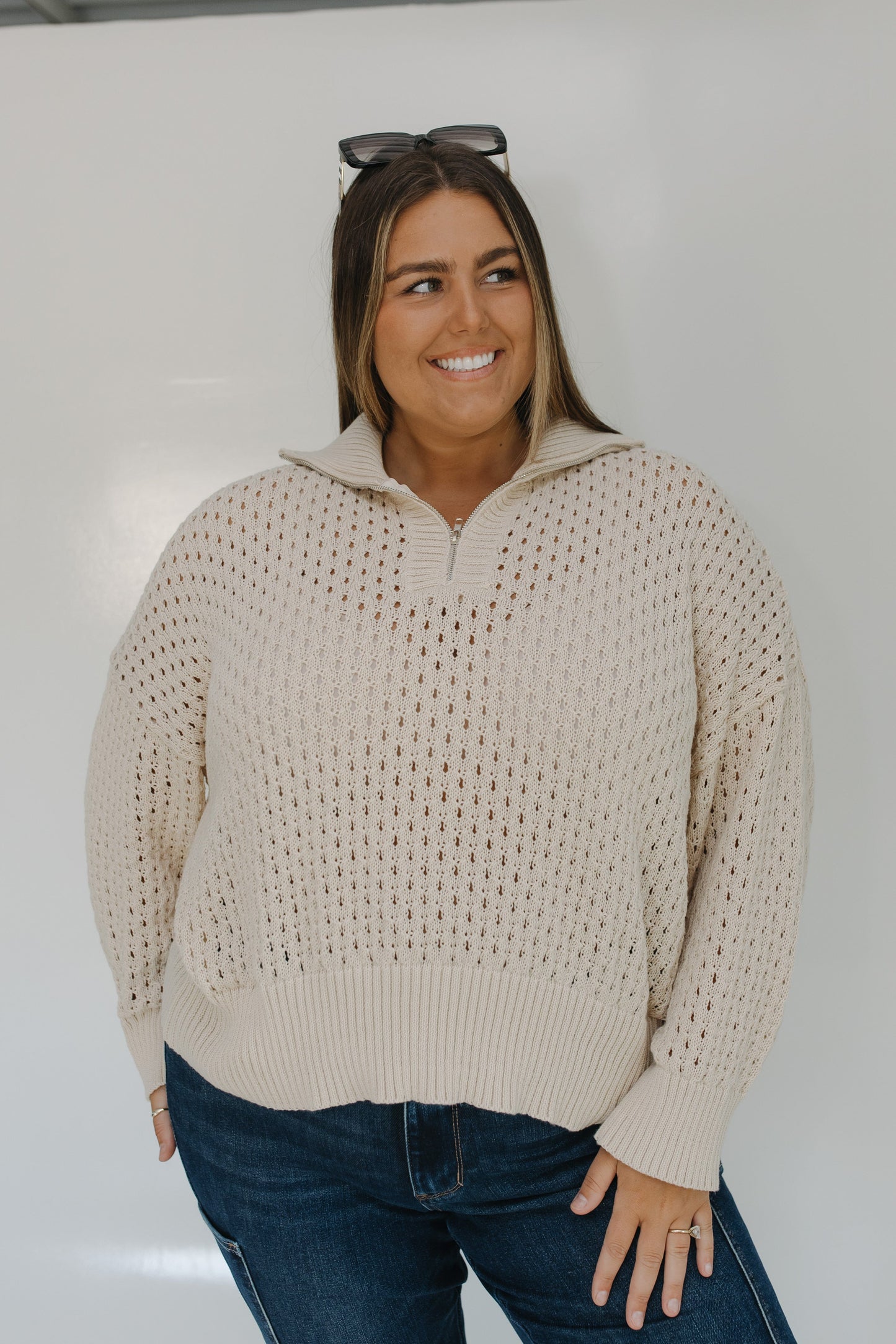 Woman wearing a beige sweater with a white background