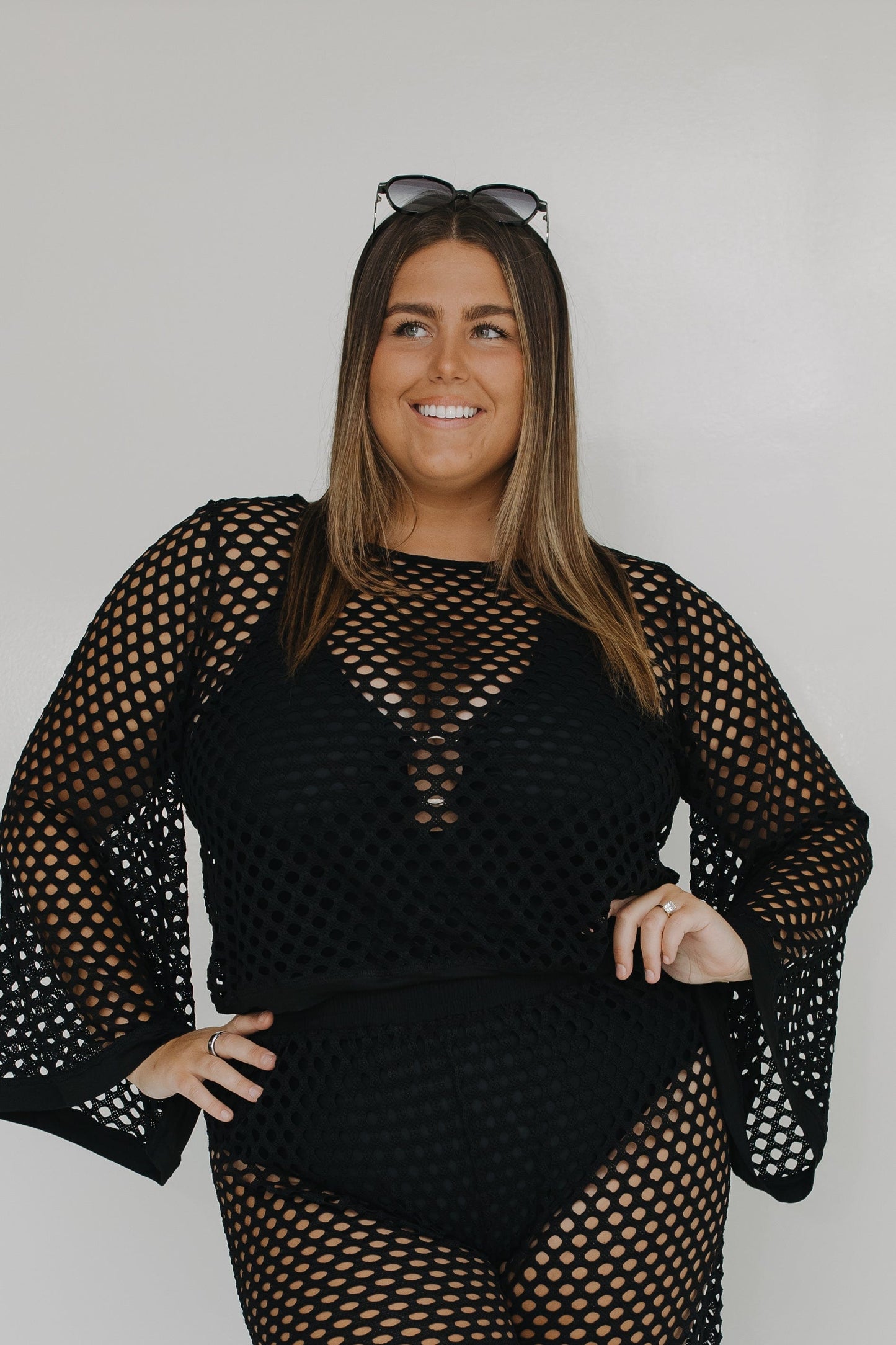 Woman wearing a black fishnet outfit against a plain background