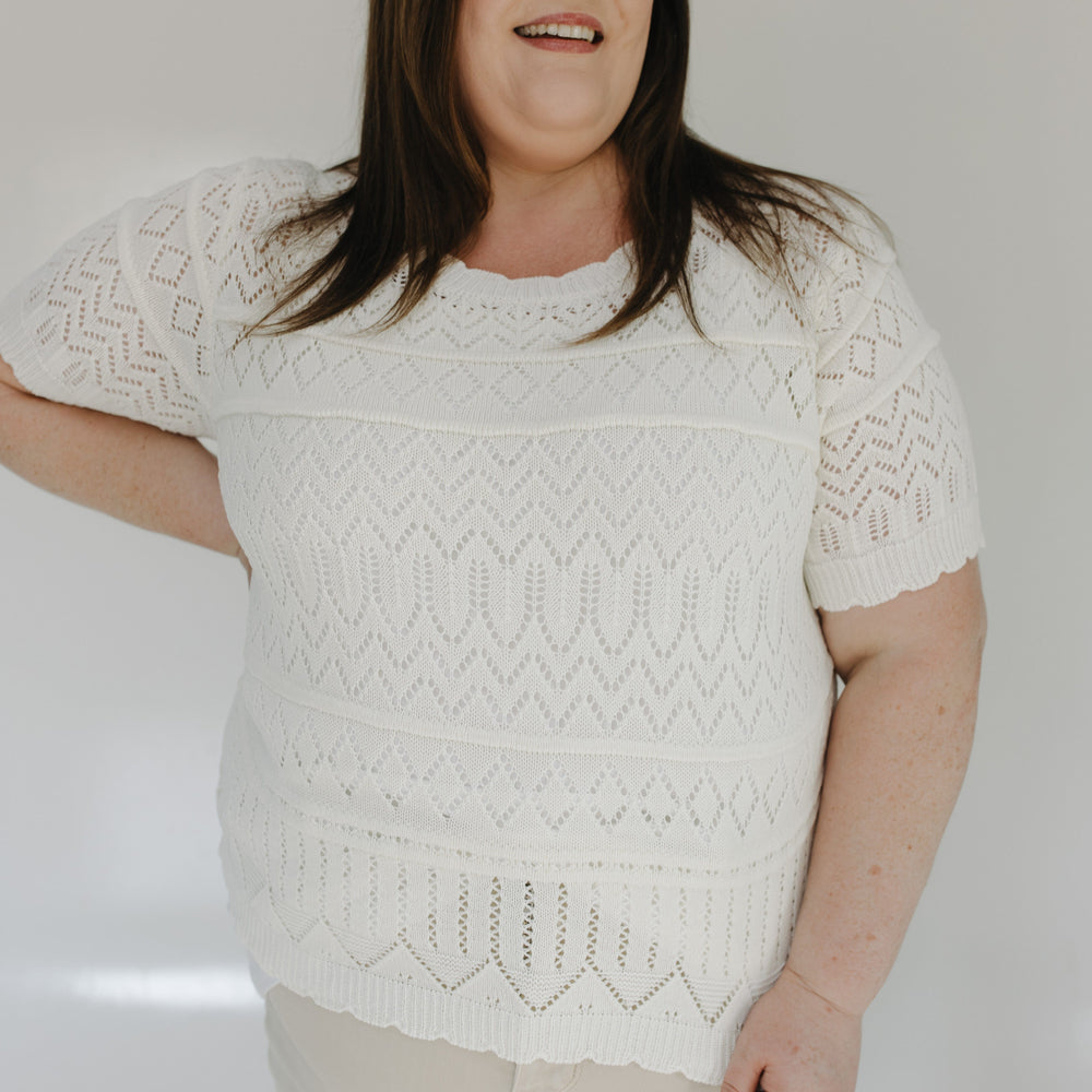Woman wearing a white patterned sweater against a plain background